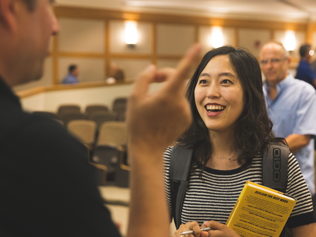 Young woman holding book and talking to man